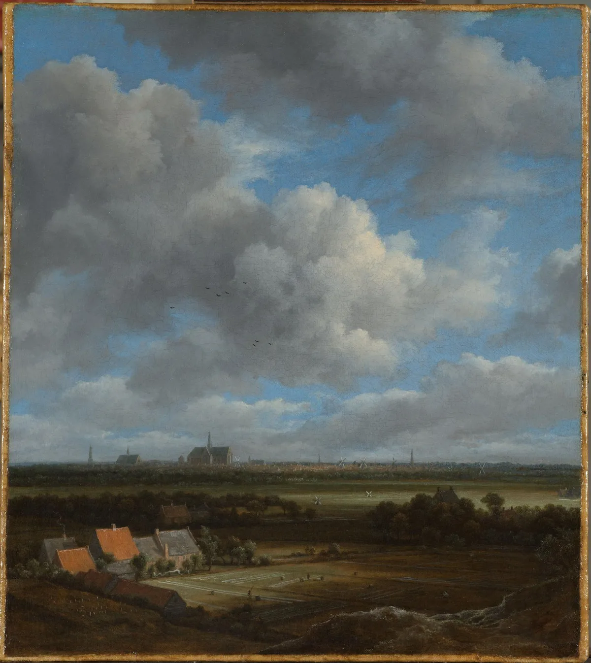 Jacob van Ruisdael's View of Haarlem showing atmospheric perspective — orange-roofed farm buildings in the foreground contrast with the softly dissolved city silhouette at the horizon
